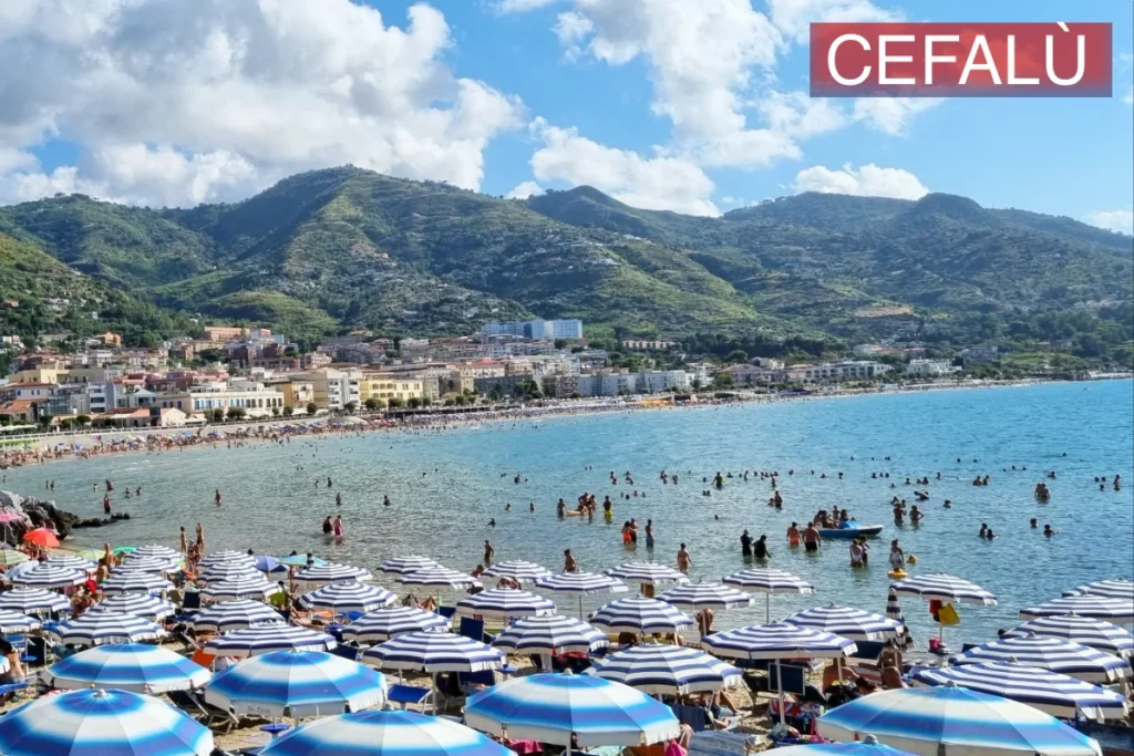 Cefalù, eine faszinierende Küstenstadt in Sizilien, die durch ihr historisches Flair und ihre atemberaubenden Strände besticht. Mit einem mit blau-weißen Sonnenschirmen geschmückten Strand bietet sie den idealen Sommerfluchtort für diejenigen, die im kristallklaren Wasser des Mittelmeers eine Abkühlung suchen.