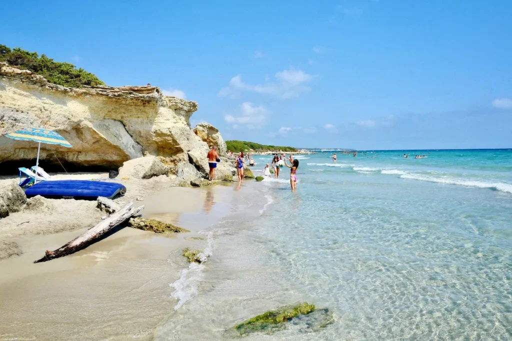 Otranto, berühmt für das klare Wasser und die weißen Sandstrände Apuliens, wo Besucher das Meer genießen. Ein sonniger Urlaubstag bietet ein vergnügliches Erlebnis neben den natürlichen Felsformationen.