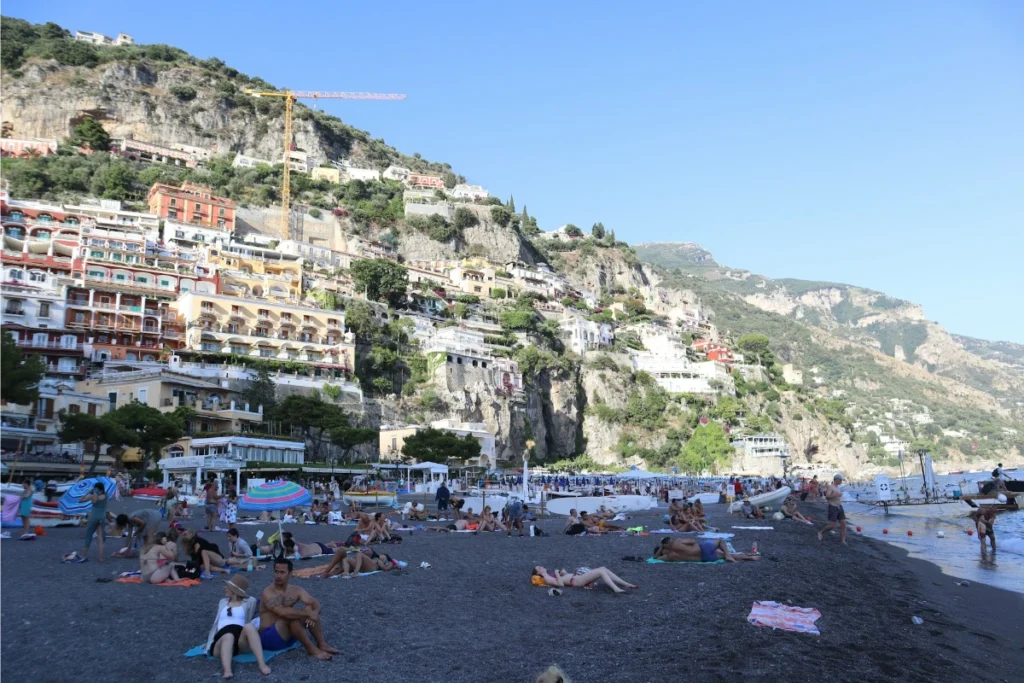 Der berühmte Spiaggia Grande Strand von Positano: Besucher sonnen sich vor der faszinierenden Kulisse der Amalfiküste und genießen die kühlen Gewässer des Mittelmeers.